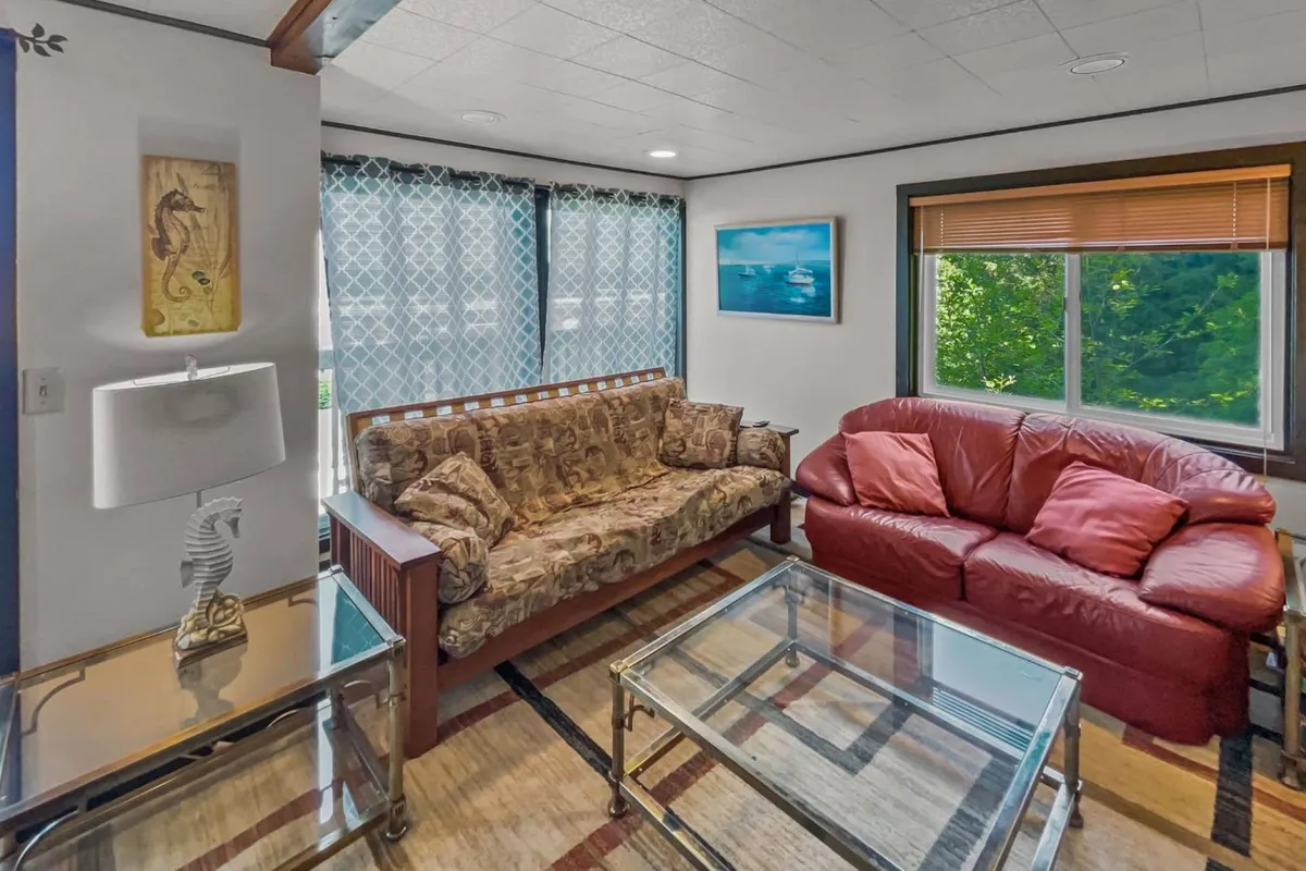 A cozy sitting area with a sofa, coffee table, lamp, and a window view that brings in abundant natural light. The scene feels calm and inviting, ideal for enjoying a morning coffee while watching the world outside—potentially spotting beachgoers or planning the next walk with your furry friend.
