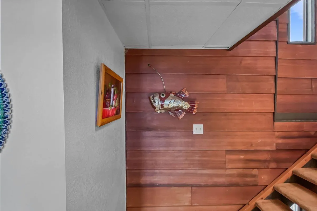 A playful entryway or landing area featuring a decorative fish mount, framed artwork, and wood paneling. The staircase and open view suggest movement between levels and evoke a sense of arrival or departure—key for exploring the surroundings.