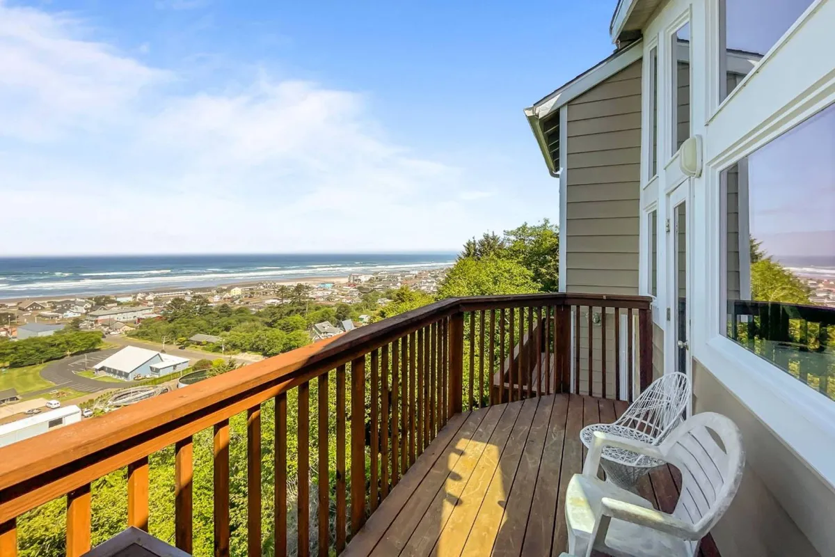 This image showcases an outdoor deck overlooking the ocean, furnished with comfortable seating and a table. The serene setting is ideal for relaxing activities like reading, enjoying a morning coffee, or dining alfresco while taking in the expansive coastal views.